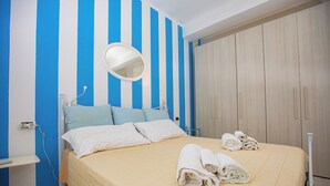Habitación de hotel con cama, mesita de noche, espejo y armario.