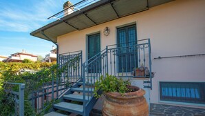 A building with a staircase, a large terracotta pot, and a metal railing. - Seaside apartment in Bengodi (Fonteblanda)