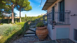 A building with a stone staircase, a large terracotta pot, and a balcony with a metal railing. - Seaside apartment in Bengodi (Fonteblanda)