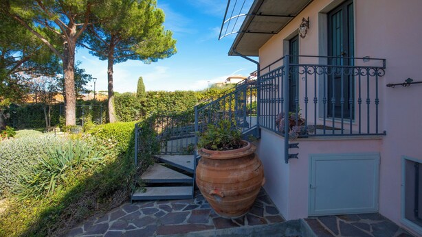 A building with a stone staircase, a large terracotta pot, and a balcony with a metal railing. - Seaside apartment in Bengodi (Orbetello)