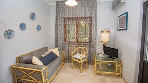 A living room with a sofa, a chair, a glass table, a lamp, and decorative plates on the wall. - Seaside apartment in Bengodi (Fonteblanda)