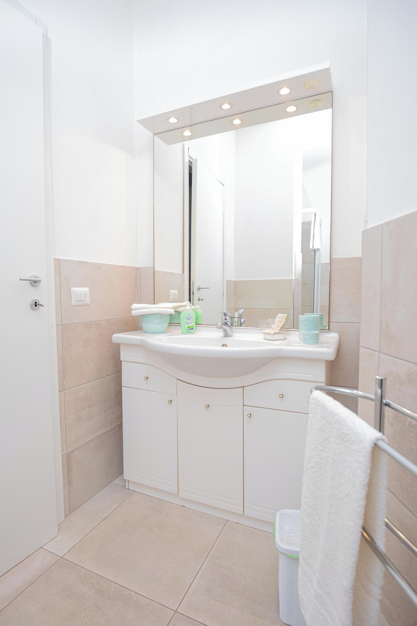 Een moderne badkamer met een wit wastafelmeubel, spiegel en betegelde vloer.