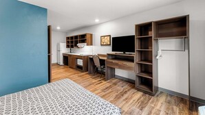 A modern bedroom with a bed, a desk, and a TV. - Woodspring Suites Kansas City Airport (Kansas City)
