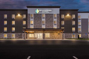 A modern hotel with a stone facade, multiple windows, and a prominent sign reading "Woodspring Suites". - Woodspring Suites Kansas City Airport (Kansas City)