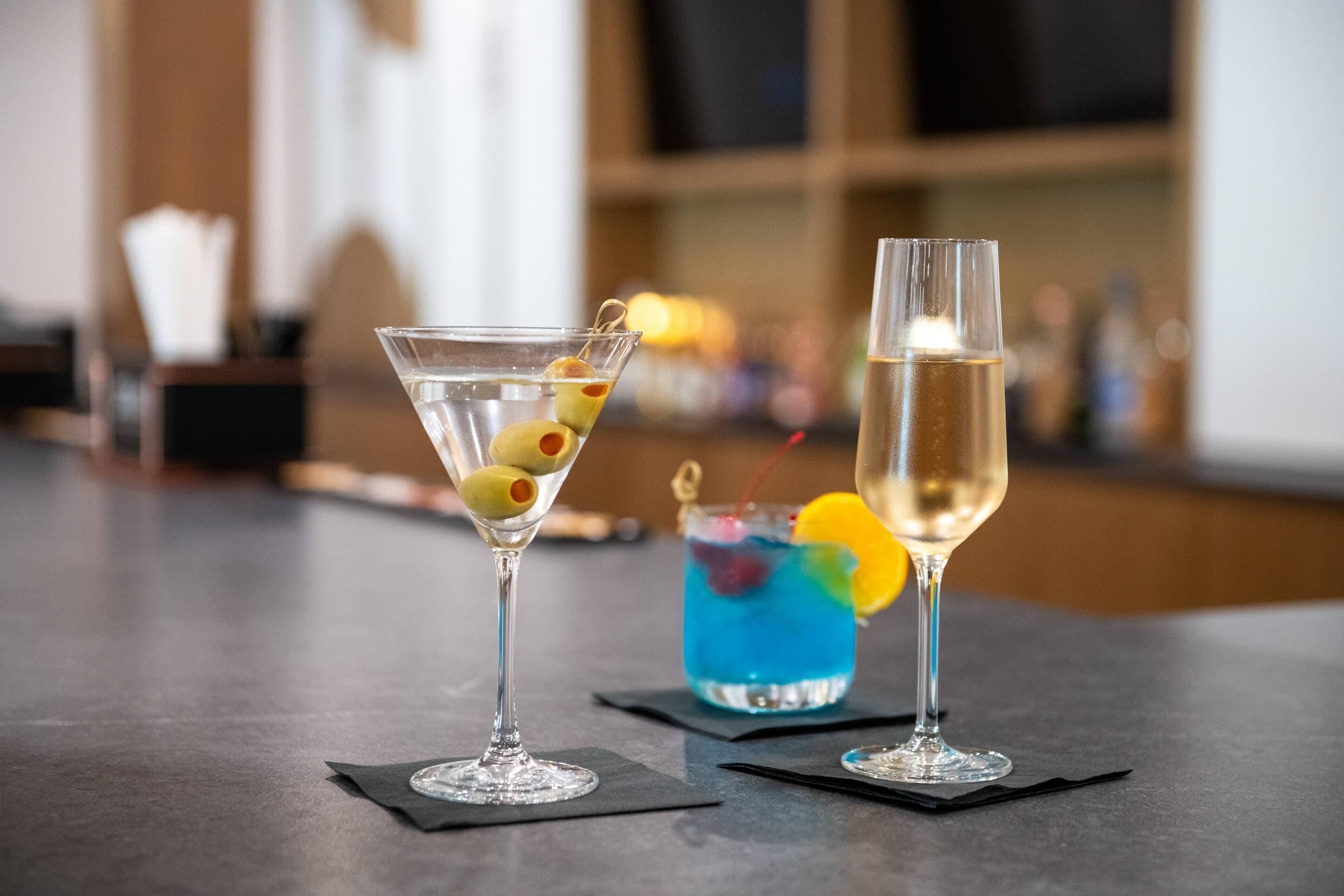Dos copas de martini sobre una barra con fondo desenfocado.