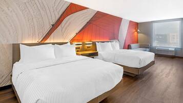 A hotel room with two beds, a large window, and a modern wall design.