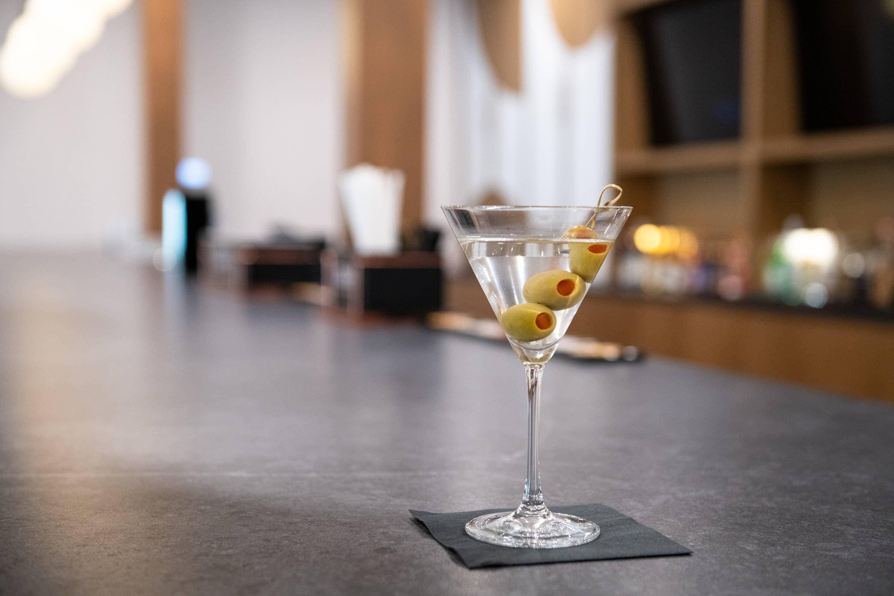 A martini glass with olives on a bar counter.