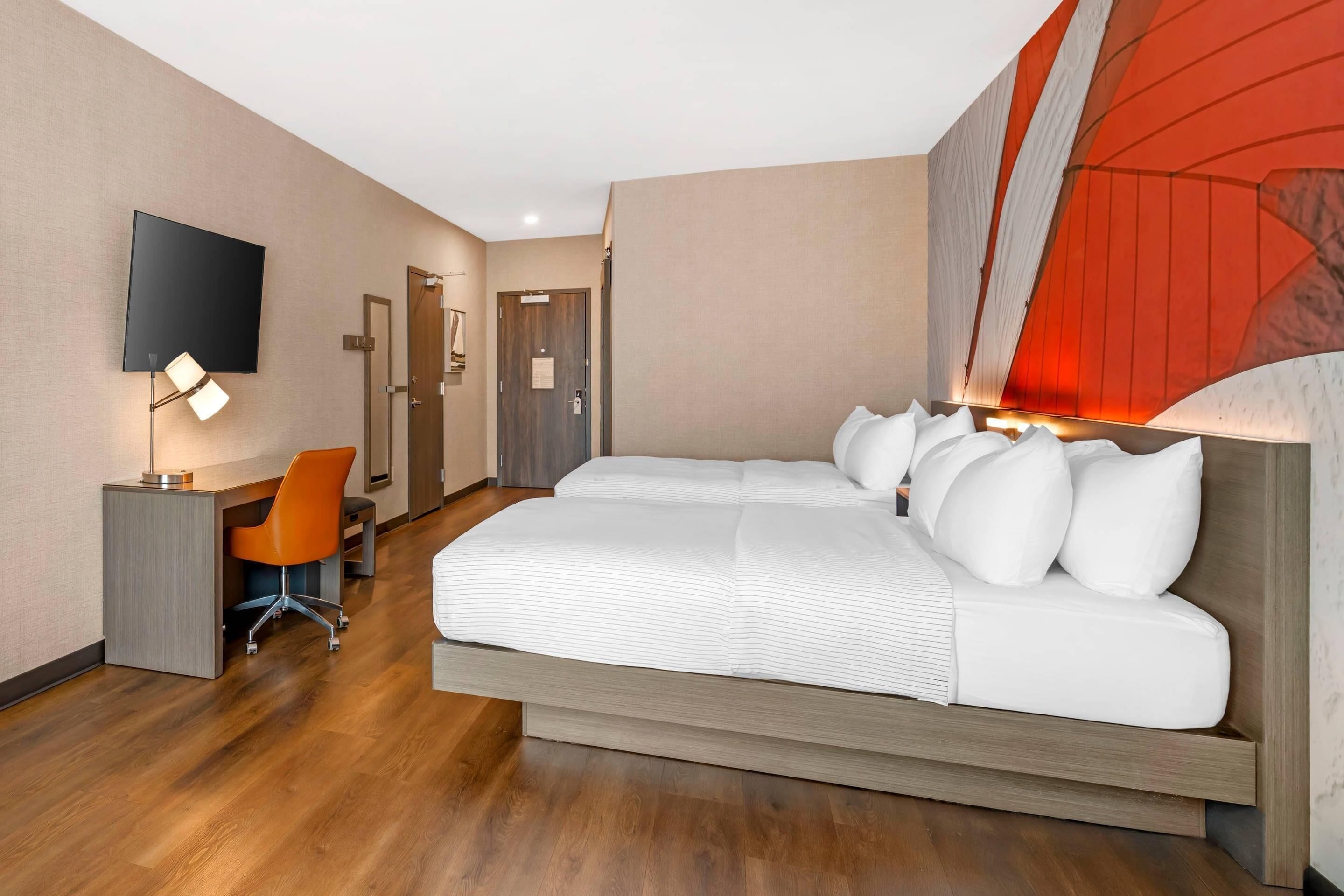 Une chambre d’hôtel avec un lit, un bureau, une chaise, une télévision et une porte.
