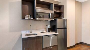 A modern kitchen with a stainless steel refrigerator, microwave, and dishwasher, wooden cabinets, and a built-in sink.