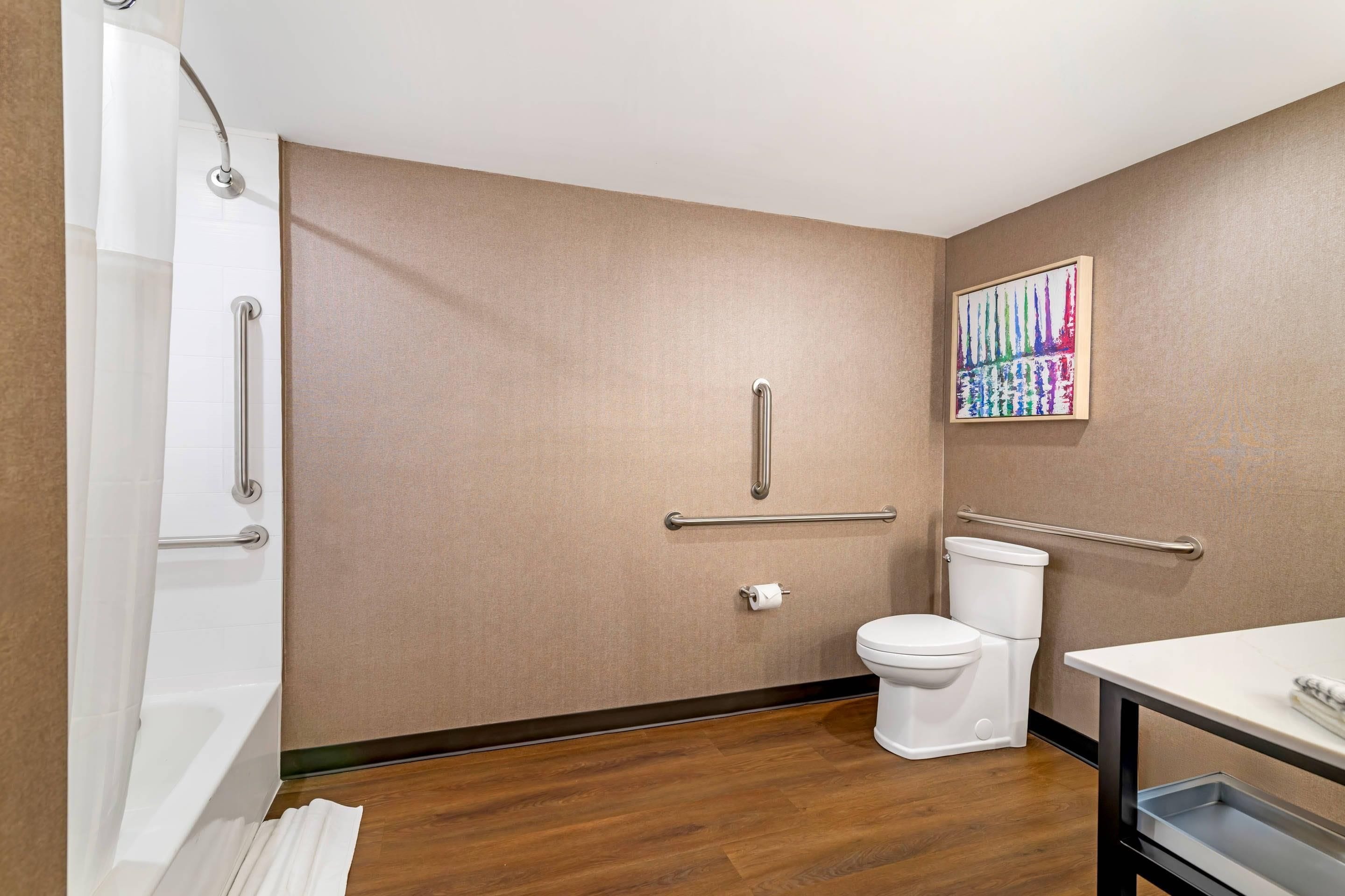 Een badkamer met douche, toilet en handgrepen.