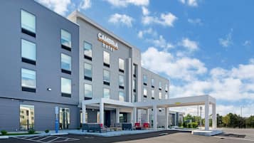 A modern hotel with a flat facade, large windows, and a covered outdoor seating area.