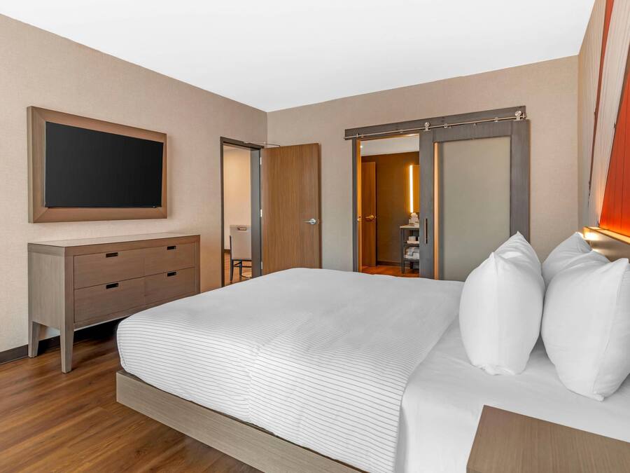 Et hotelværelse med en seng, et skrivebord, et fjernsyn og et klædeskab.
