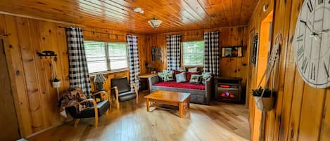 L’intérieur d’un chalet accueillant, avec un canapé, des fauteuils, une table et une cheminée.