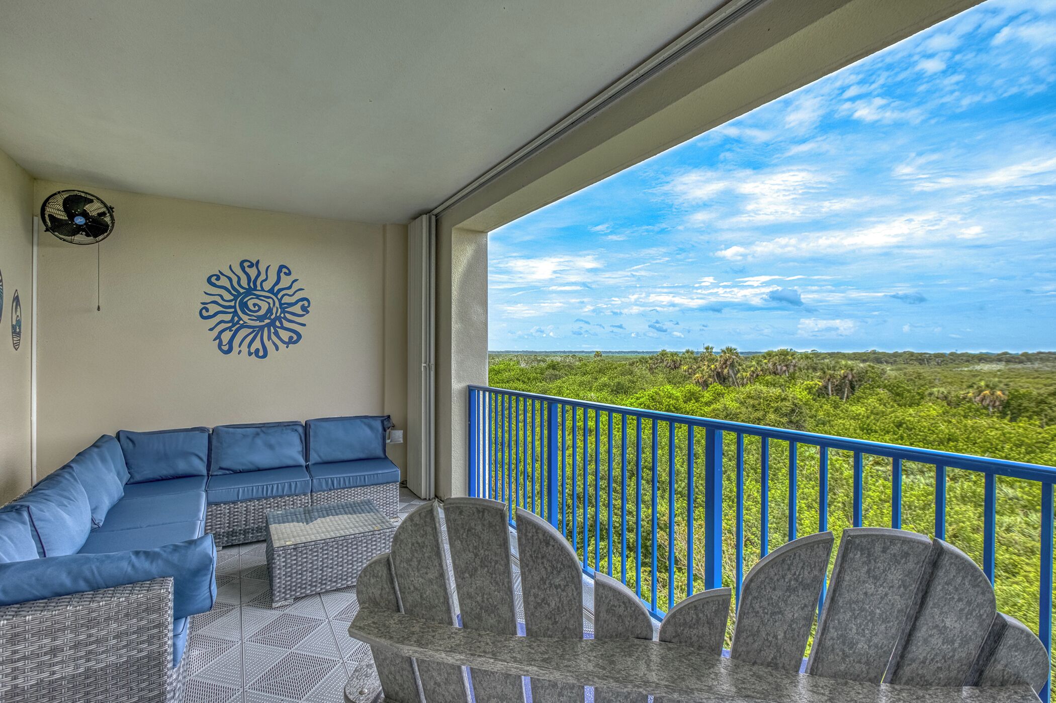 A balcony with a blue railing, a blue sofa, and a table with chairs.