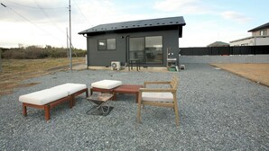 Une maison moderne dotée d’un patio comprenant un banc en bois, une petite table et une chaise.
