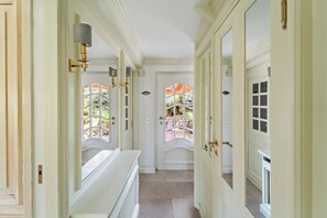 A hallway with white doors, a radiator, and a view of an outdoor patio. - Avenarius Hüs - Reet. Kampen. Garten (Kampen (Sylt))