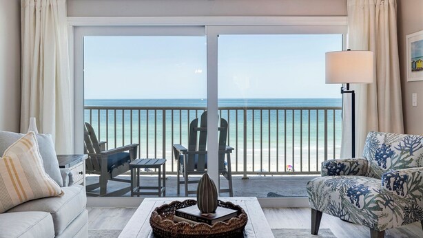 A room with a balcony overlooking the ocean, featuring a sofa, chairs, a lamp, and a decorative vase. - Seagate 307—Oceanfront Condo w/ Gulf Balcony, Pool Access & Walkable Dining in Indian Shores (Indian Shores)