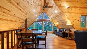 Ein Holzinterieur mit einem Esstisch, Stühlen und einer Couch. Ein Schild weist auf den 