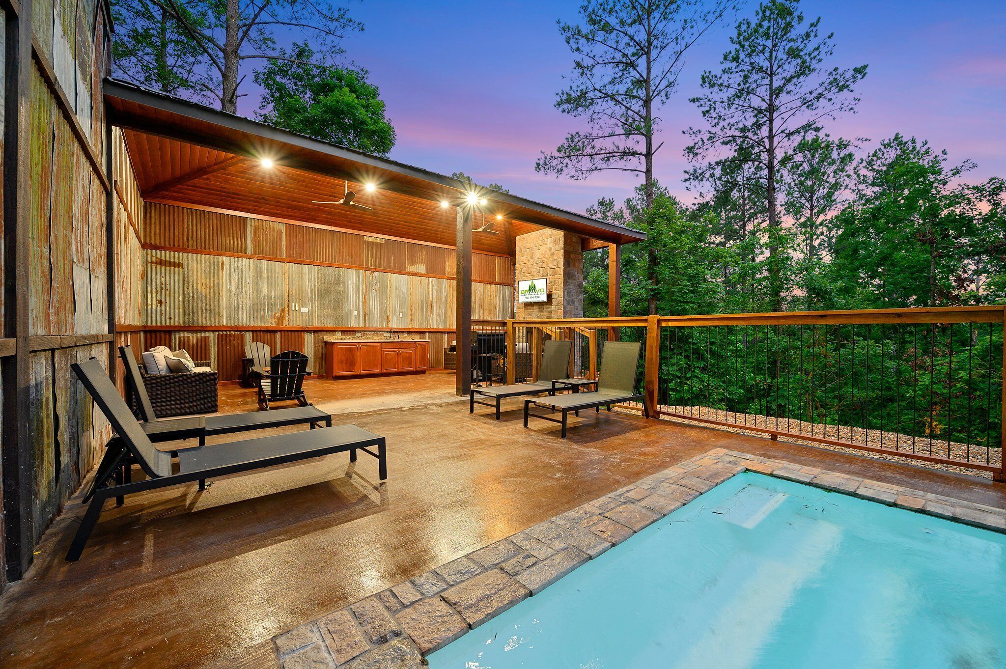 A covered outdoor area with a pool, lounge chairs, and a fireplace.