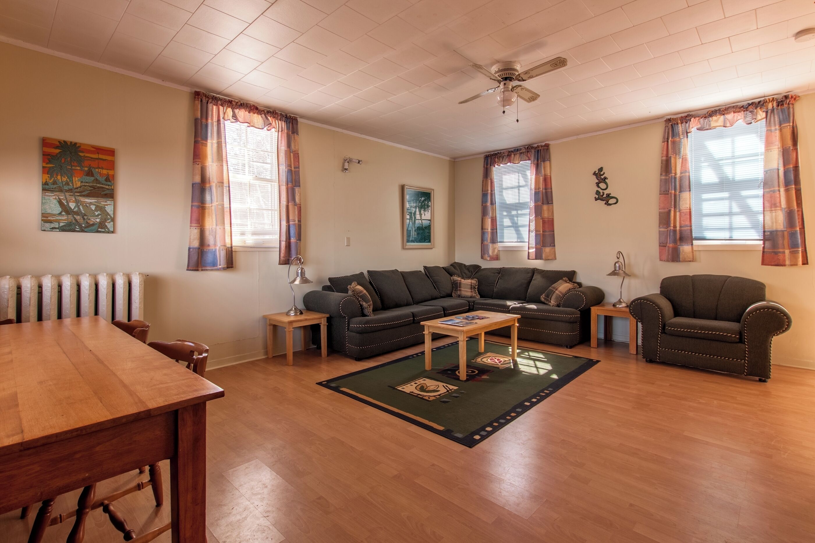 Una sala de estar con una mesa de comedor de madera, un sofá, una mesa de centro y un ventilador de techo.