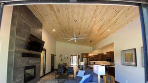 A spacious living room with a fireplace, a large sofa, and a ceiling fan. - Custom home close to ski resort with hot tub (Angel Fire)