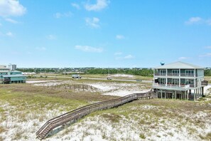 A coastal house with a wooden deck and a view of the beach. - "Sandy Feet Retreat" | Beachfront | Private Pool | Beach Getaways (Pensacola)