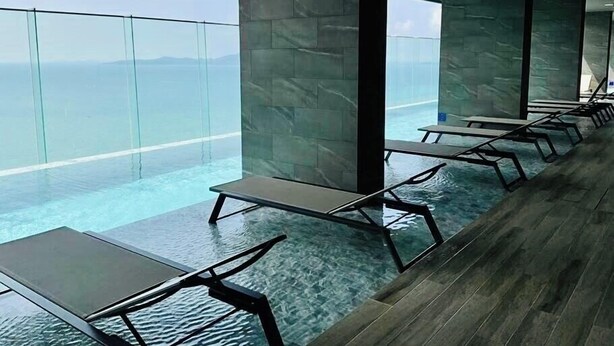 A modern indoor pool area with clear glass walls and a view of the ocean. - The Panora Pattaya by PSR (Pattaya)