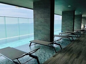 A modern indoor pool area with clear glass walls and a view of the ocean. - The Panora Pattaya by PSR (Pattaya)