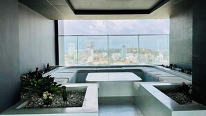 A modern interior with a large window offering a city view, a seating area with planters, and a minimalist design. - The Panora Pattaya by PSR (Pattaya)