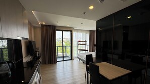 A modern hotel room with a balcony, a dining area, and a TV. - The Panora Pattaya by PSR (Pattaya)