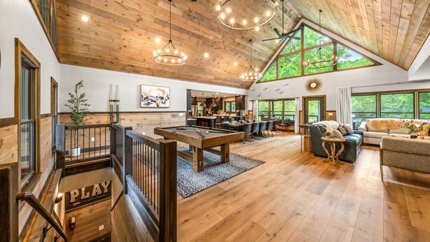 A spacious living area with a pool table, comfortable seating, and large windows offering natural light and views of the outdoors. - Family Escape w/Golf Sim, Pool, Theater, Arcade (Sevierville)