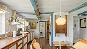 A kitchen with wooden cabinets, a dining area with a table and chairs, and a hallway leading to a living room. - 4 bedroom gorgeous home in Rødby (Rødby)