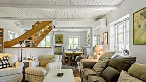 A cozy living room with a wooden staircase, a dining table, and various seating options. - 4 bedroom gorgeous home in Rødby (Rødby)