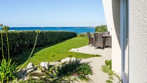 A patio with a view of the sea, a hedge, and a building facade. - Les Pieds dans l'eau by Interhome (Cléder)