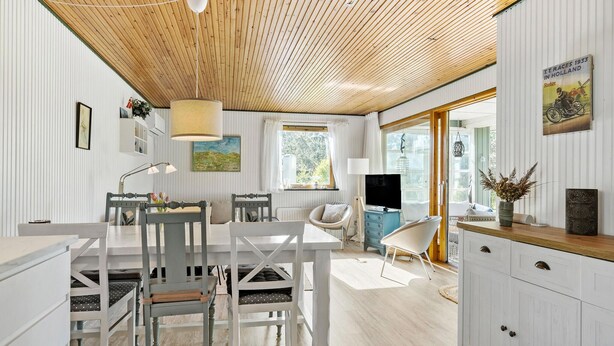 A spacious room with a wooden ceiling, a dining area with a white table and chairs, a TV, and a window with curtains. - 3 bedroom awesome home in Vig (Vig)