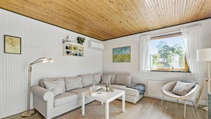 A cozy living room with a striped sofa, a white coffee table, and a window with curtains. - 3 bedroom awesome home in Vig (Vig)