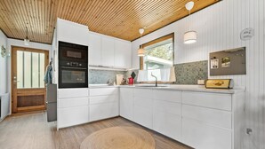 A modern kitchen with white cabinetry, a wooden ceiling, and a large window. - 3 bedroom awesome home in Vig (Vig)