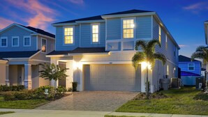 A two-story residential house with a garage, a driveway, and a well-maintained lawn. - Sunset Getaway ~ Game-room, Pool, Close to Disney (Davenport)