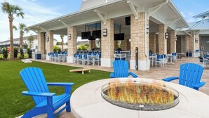 An outdoor patio area with blue Adirondack chairs, a fire pit, and a covered seating area with tables and chairs. - Sunset Getaway ~ Game-room, Pool, Close to Disney (Davenport)