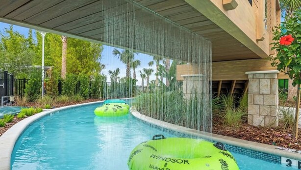 A swimming pool with two green inflatable tubes labeled 'Windsor Island Resort'. - Sunset Getaway ~ Game-room, Pool, Close to Disney (Davenport)