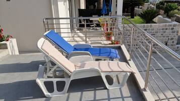 A poolside area with sun loungers and a stone wall.