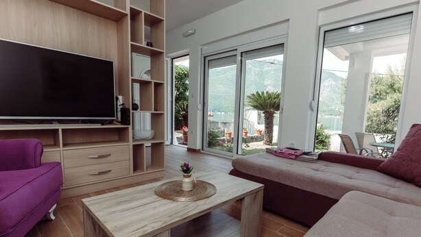 Ein modernes Wohnzimmer mit Flachbildfernseher, Holzregalen, einer Couch und einem Couchtisch.