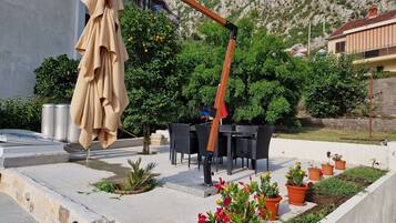 Eine Terrasse im Freien mit Tisch und Stühlen, umgeben von Blumentöpfen und einer Holz-Pergola.