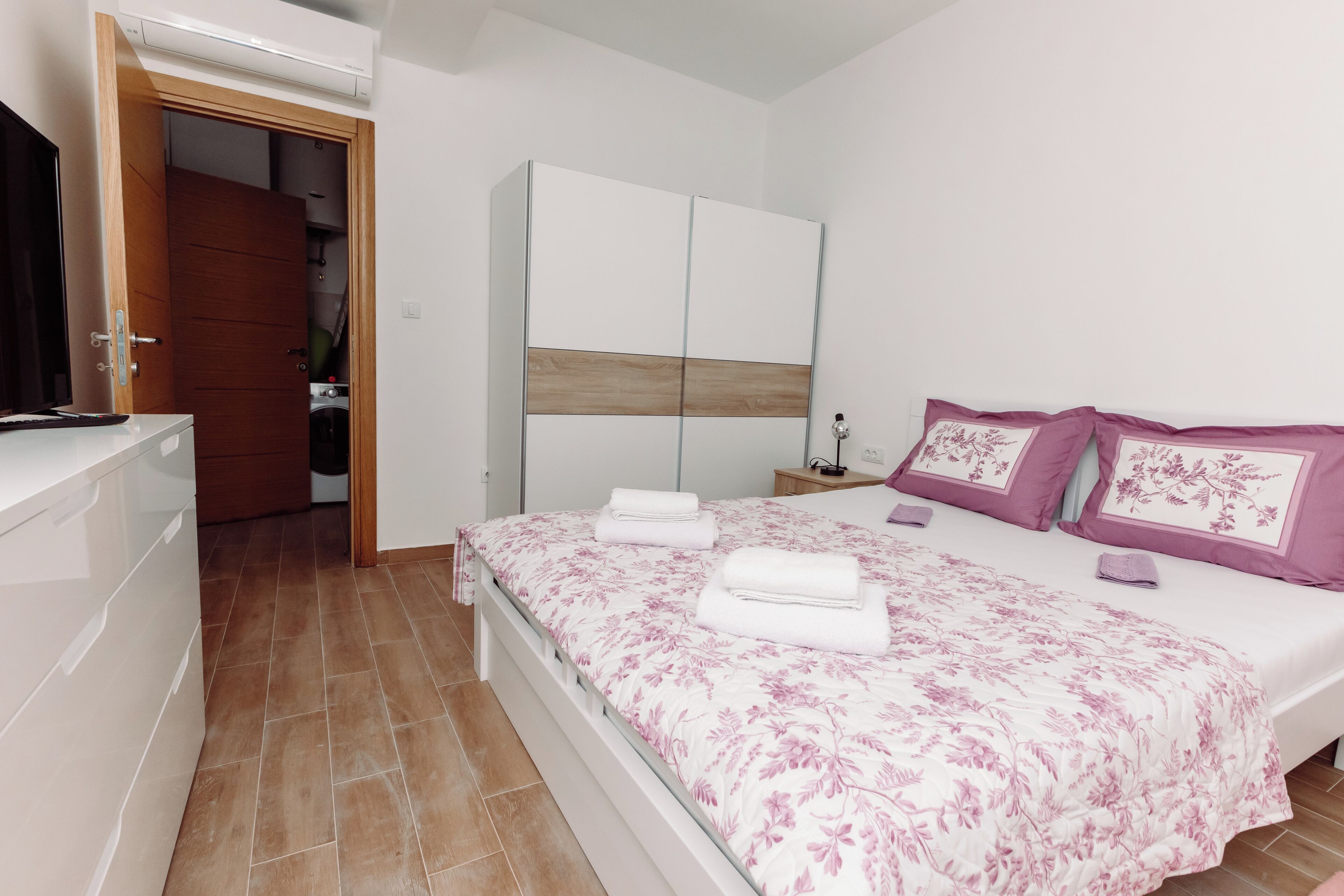 A bedroom with a bed, a wardrobe, and a bathroom visible through an open door.