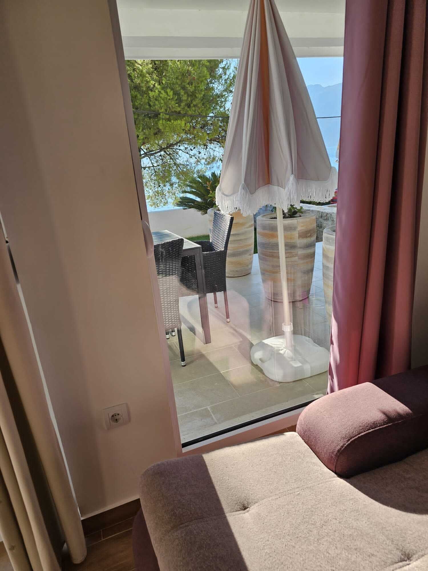 A room with a large window, a cushioned seating area, and a hanging chair with a white canopy.