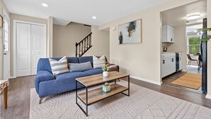 Un salon avec un canapé bleu, une table basse en bois et un tableau accroché au mur.