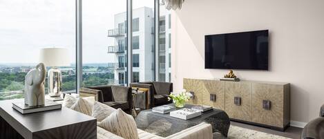 A modern living room with a large window, a flat-screen TV, a sofa, a coffee table, and a decorative sculpture.
