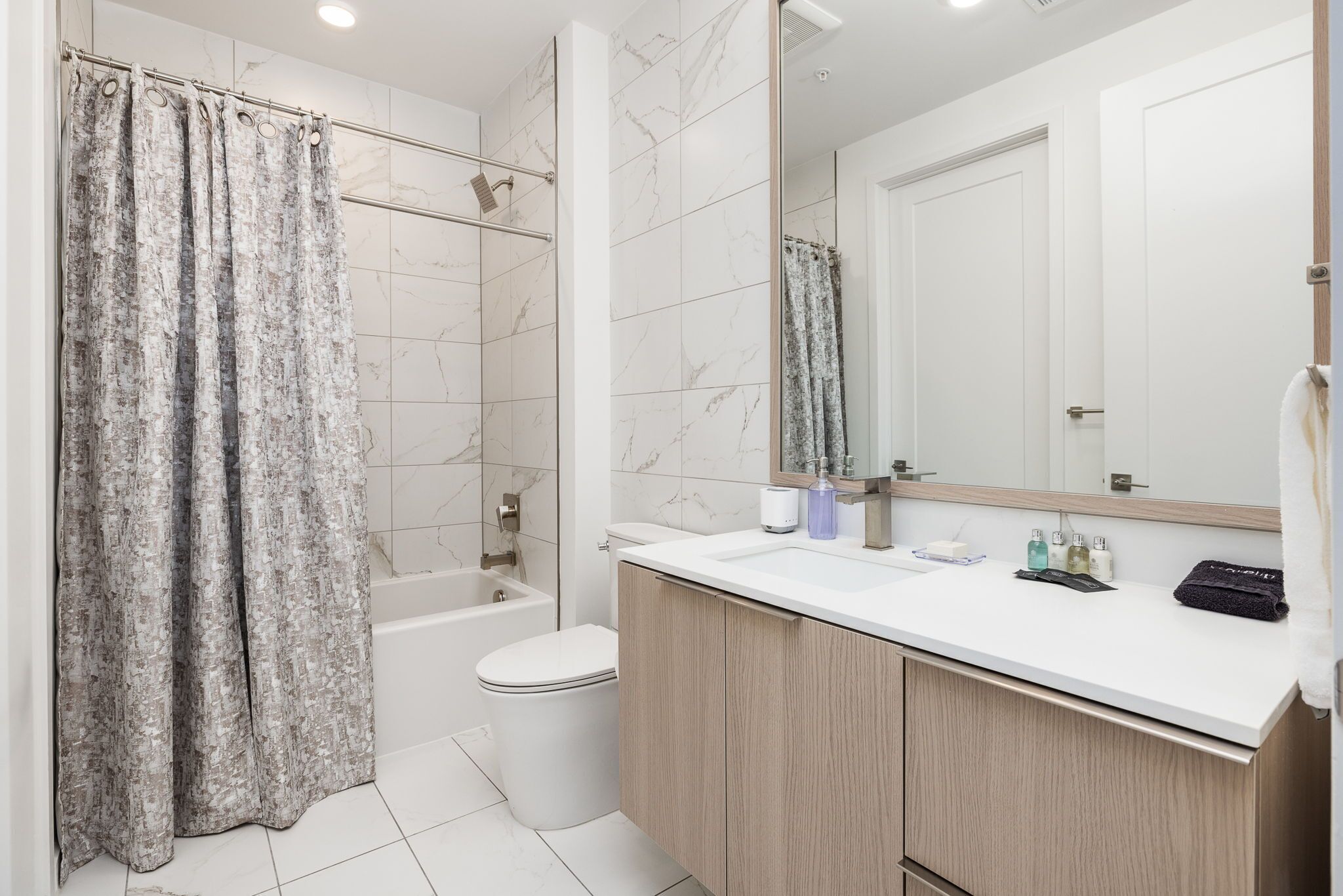 A modern bathroom with a bathtub, toilet, and a vanity with a mirror.