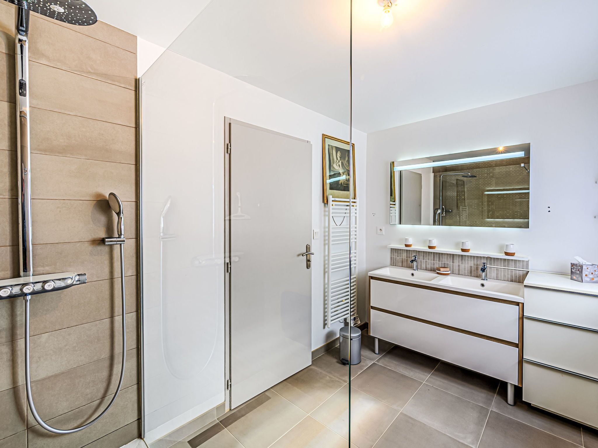 A modern bathroom with a glass shower enclosure, a vanity with a mirror, and a towel rack.