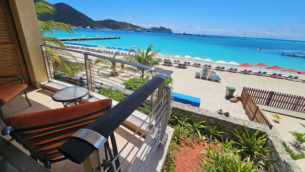 Un balcone con vista sulla spiaggia, sedie a sdraio e ombrelloni.